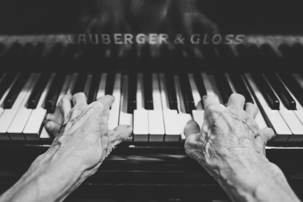 Free Image of Close-up of elderly hands playing the piano with intense concentration. 