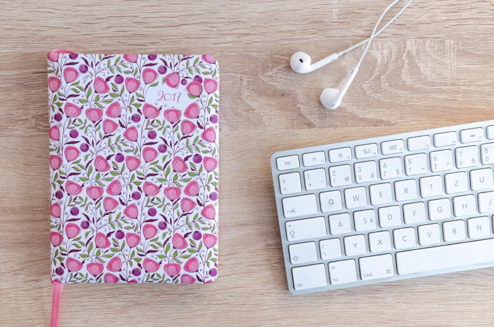 Free Image of Floral patterned notebook with headphones and keyboard on desk 