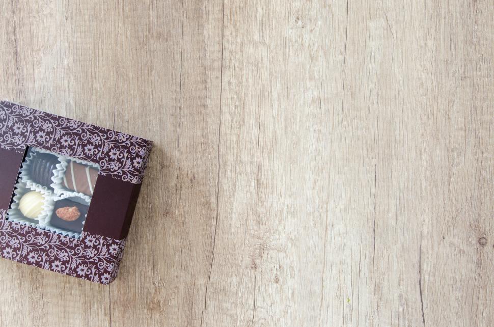 Free Image of Box of assorted chocolates on wooden surface with decorative design 