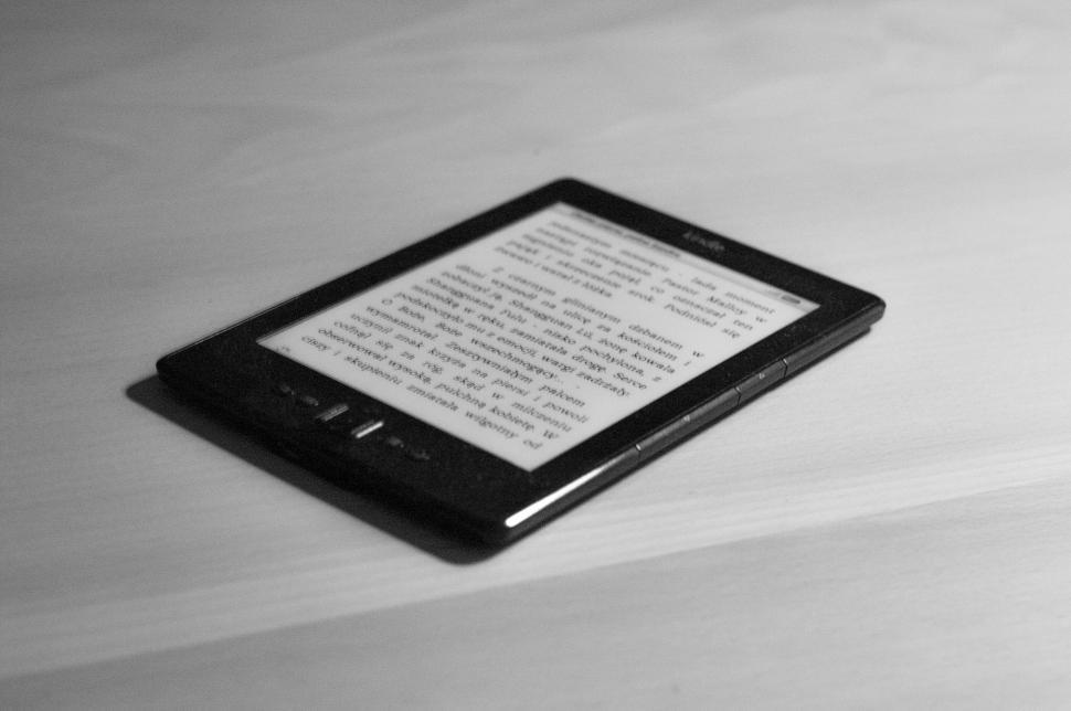 Free Image of Black e-reader with text on a wooden surface, angled view. 