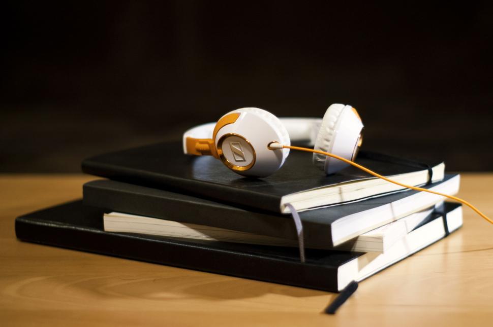 Free Image of White orange headphones on stacked black notebooks 