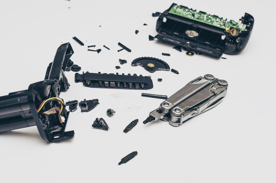 Free Image of Disassembled electronic device parts with a multitool on white background. 