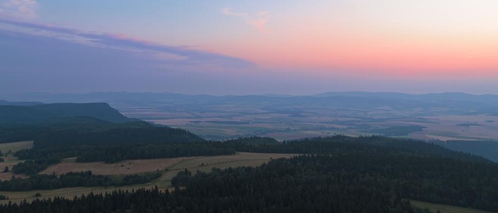 Free Image of Panoramic view of distant hills and fields during sunset time. 