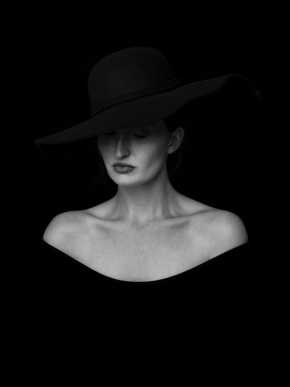 Free Image of Woman in a black hat and off-shoulder dress against black backdrop 