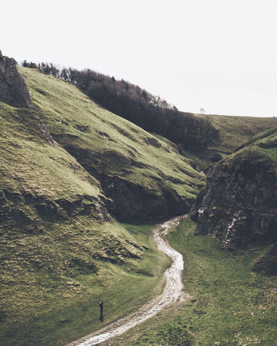 Free Image of Serene valley with rocky hills and a small winding path below. 