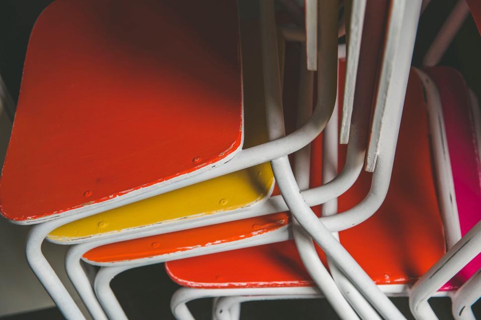 Free Image of Brightly colored stack of school chairs with red, yellow, orange seats. 