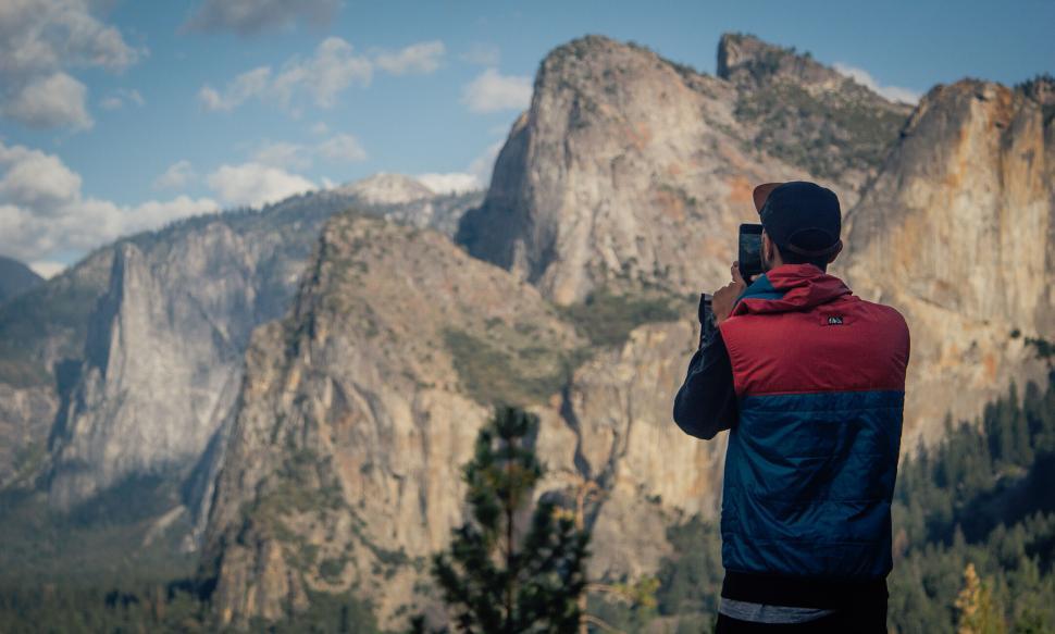 Free Image of Traveler photographing majestic mountain peaks in bright daylight 