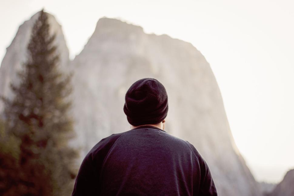 Free Image of Person facing massive mountain cliff under clear bright sky 