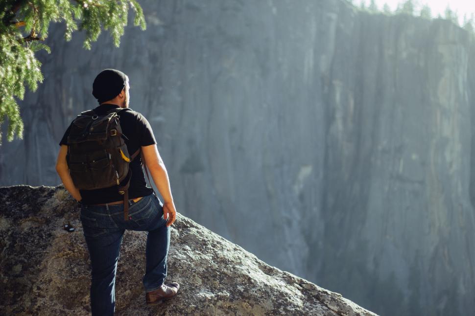 Free Image of Adventurer standing on cliff edge looking at distant mountains 