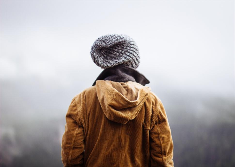 Free Image of Individual in outdoor clothing overlooking a misty mountainous view 