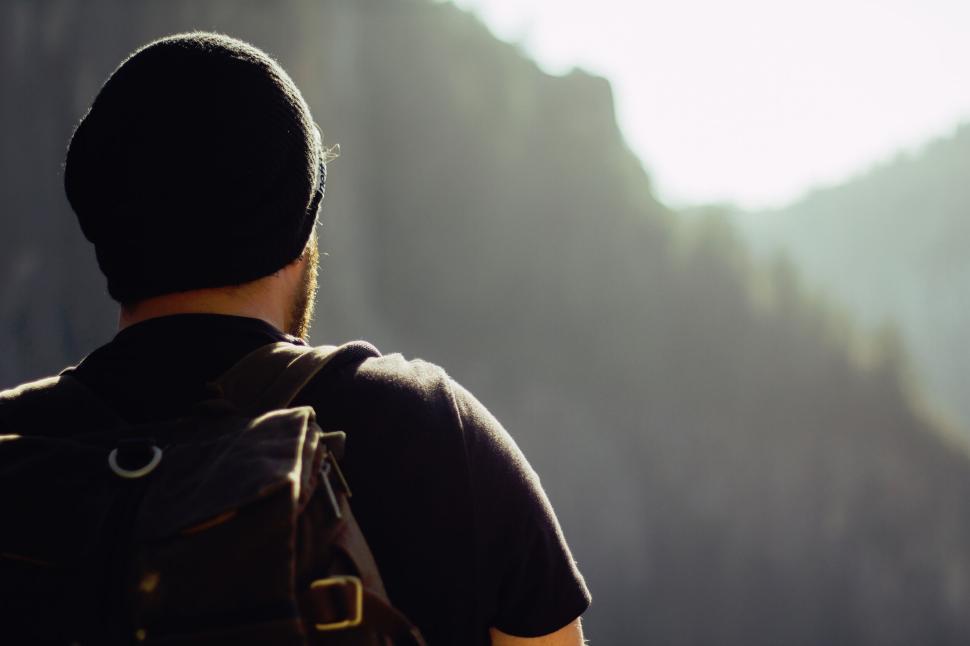 Free Image of Hiker with backpack looks at mountain view on a bright day 