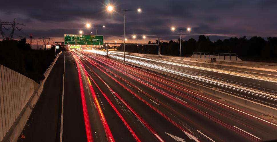 Free Image of Busy highway under an evening sky filled with light trails of cars 
