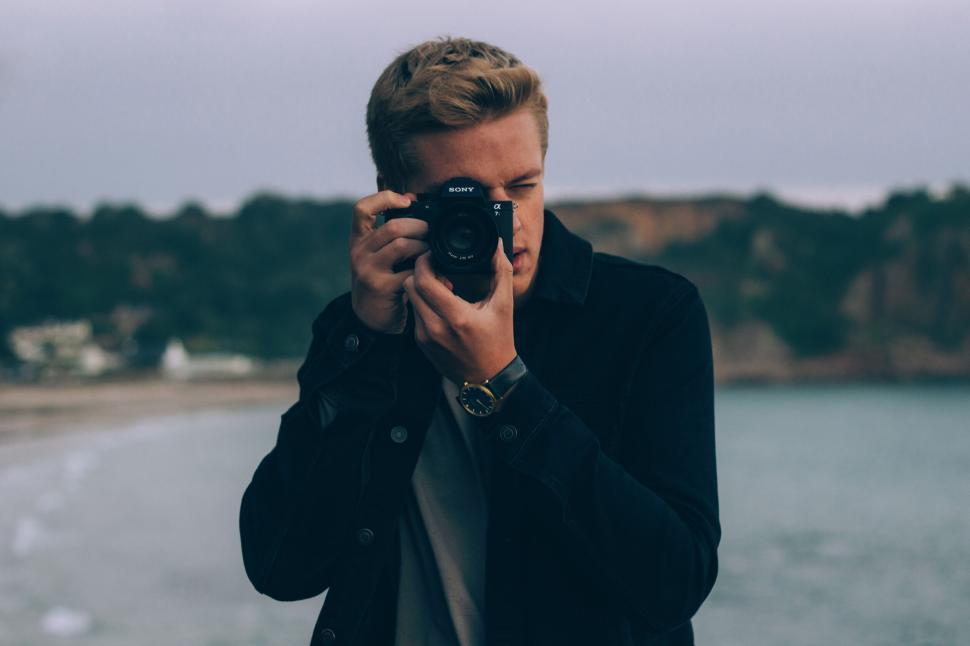 Free Image of Person capturing a scenic photograph by the seaside during sunset. 