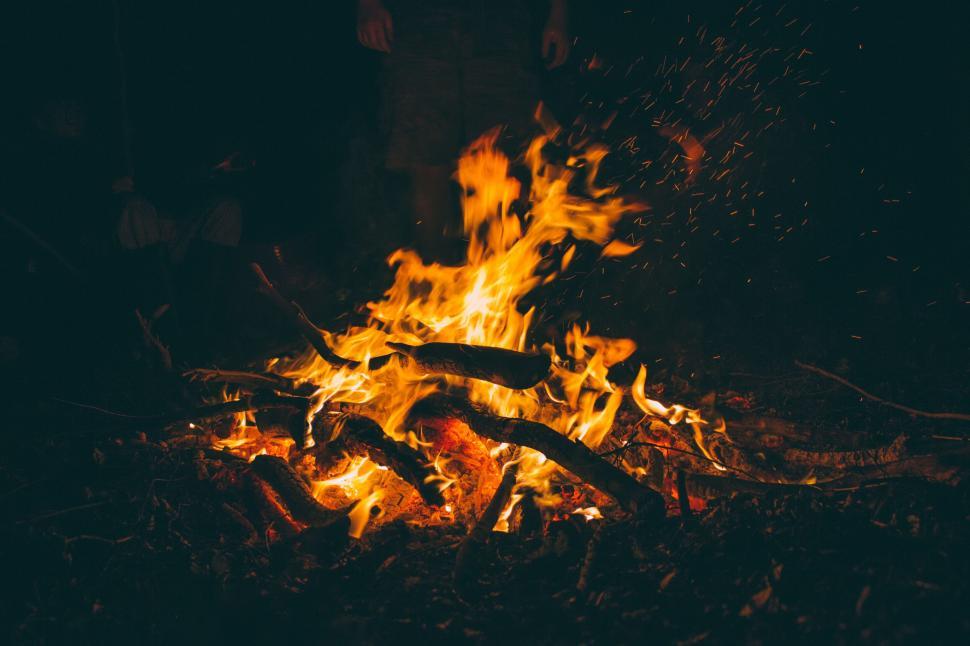 Free Image of Campfire with glowing flames and sparks against a dark night backdrop. 
