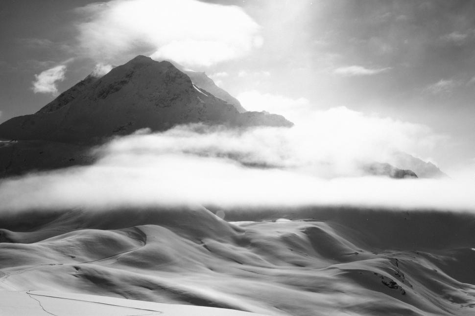 Free Image of Snow-covered mountains with dramatic clouds wrapping the peaks. 