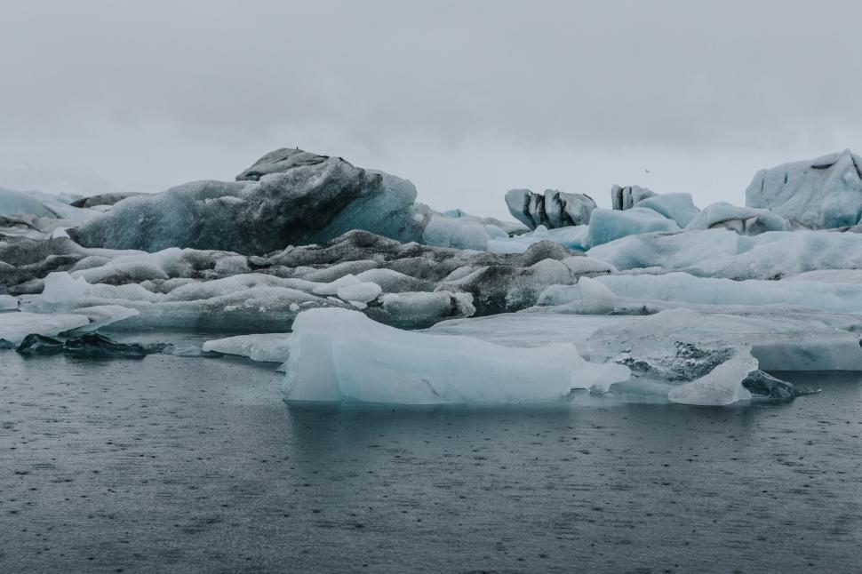 Free Image of Frozen icebergs floating in a cold, gray Arctic seascape. 