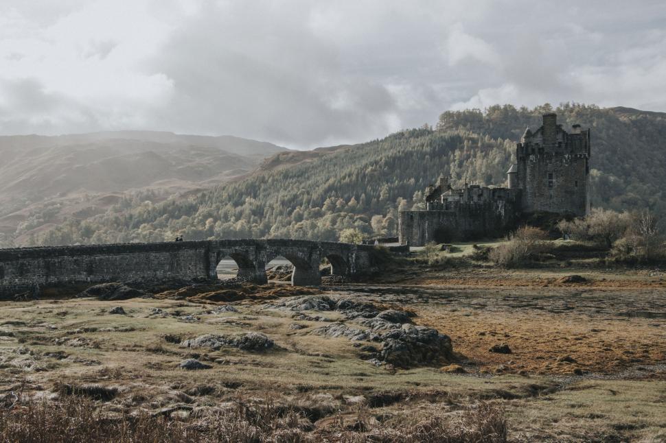 Free Image of Medieval castle with stone bridge over scenic valley landscape view 