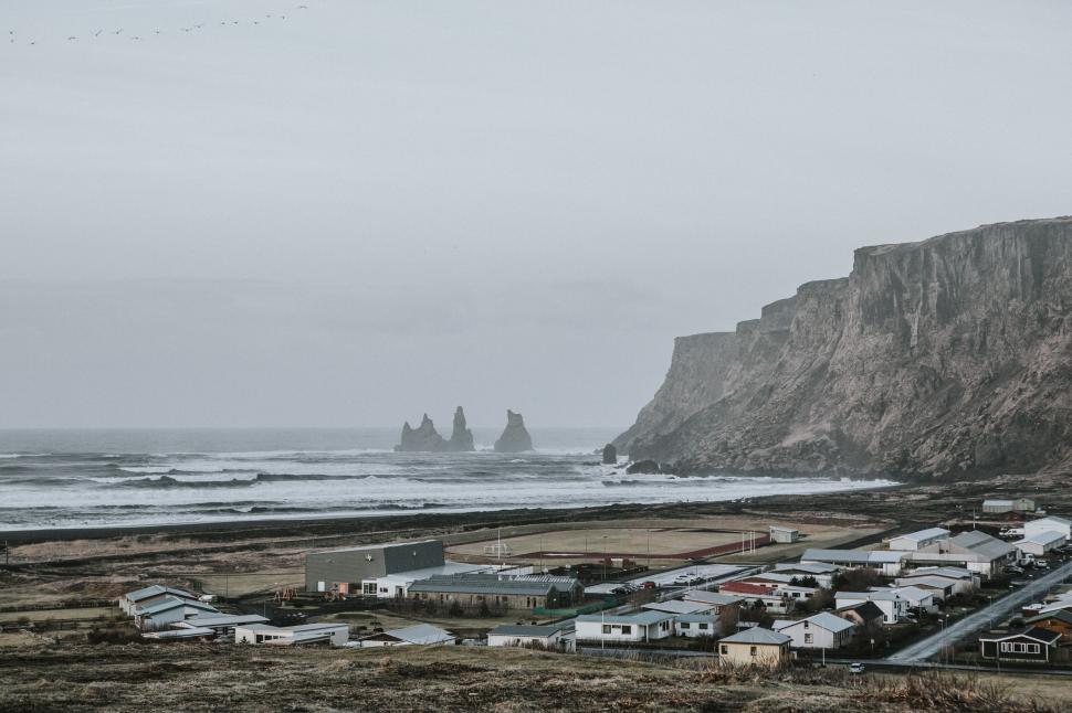 Free Image of Coastal village at the base of dramatic cliffs by the ocean 