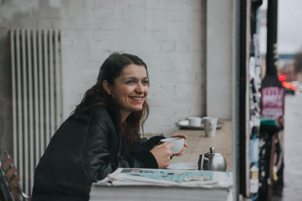 Free Image of A woman smiling while drinking coffee in a cozy cafe 