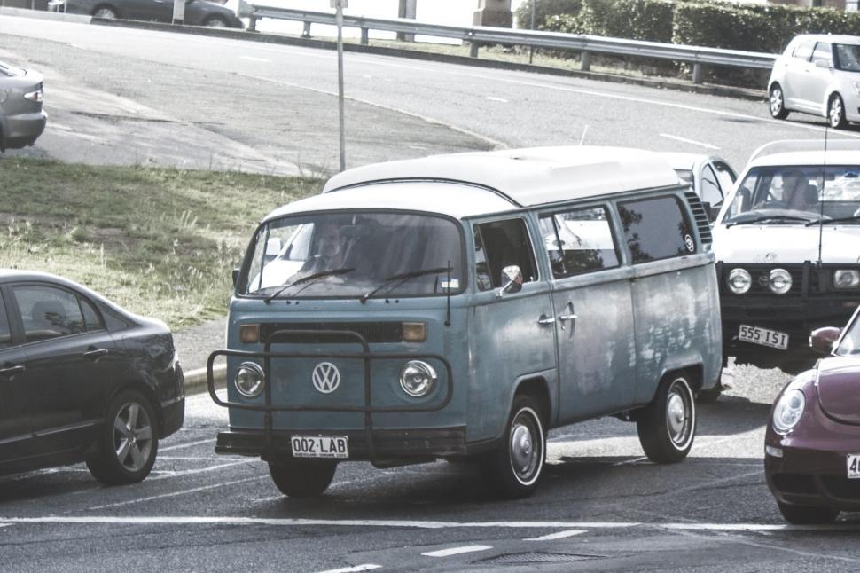 Free Image of Vintage Volkswagen van driving on a busy road with other vehicles 