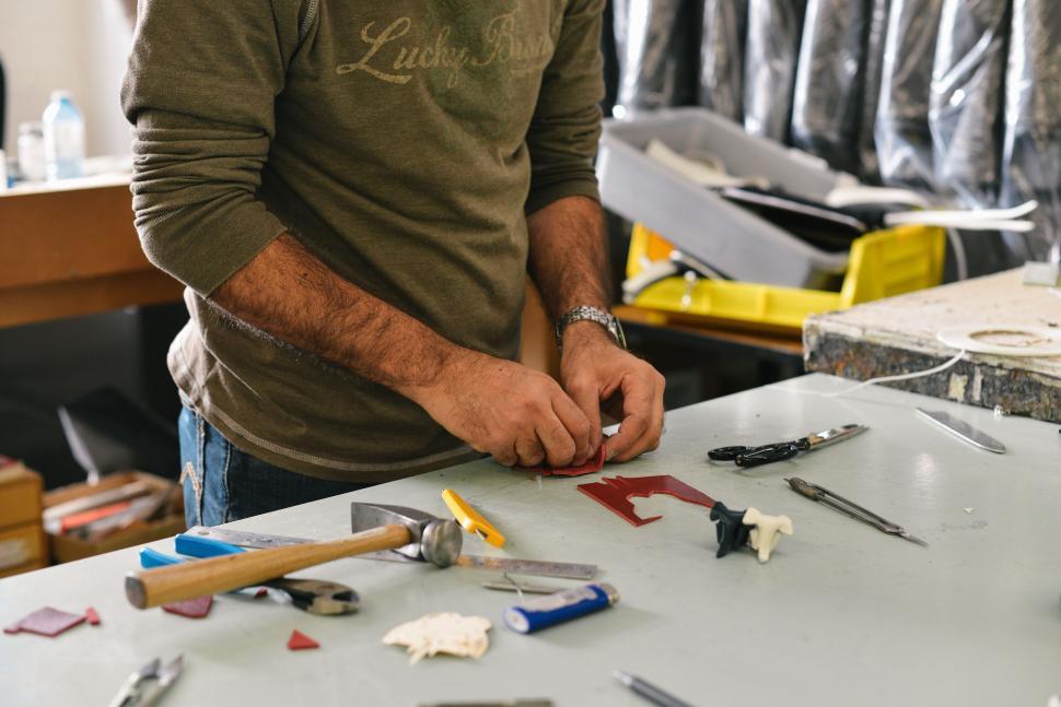 Free Image of A man working with tools on a craft project at a workshop table 
