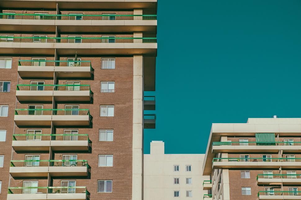 Free Image of Modern apartment buildings with green accents on a sunny day. 