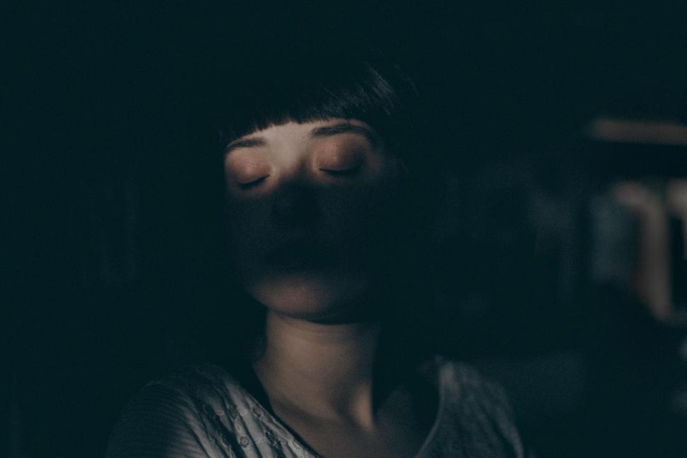 Free Image of Person in shadow with closed eyes, illuminated by a soft light. 
