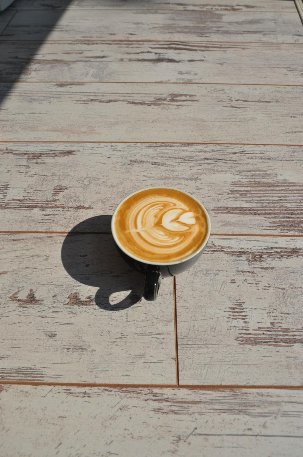 Free Image of Cup of latte with frothy heart design on light wooden table. 