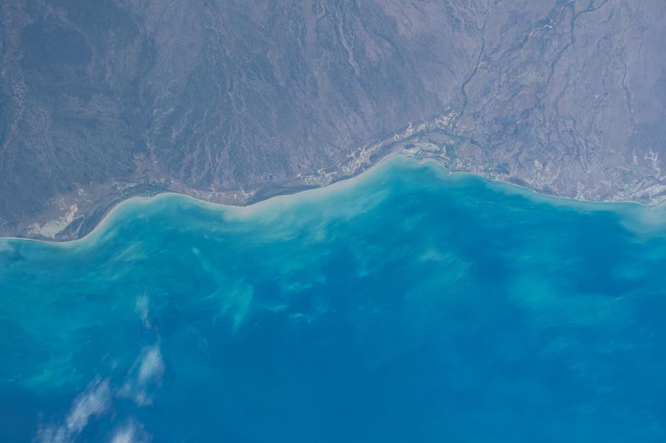 Free Image of Aerial view of a coastal region with clear blue waters and land. 