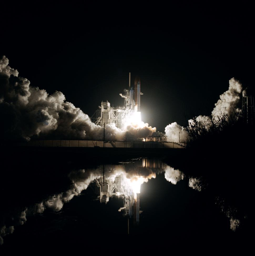 Free Image of Nighttime space shuttle launch with reflection on water surface. 