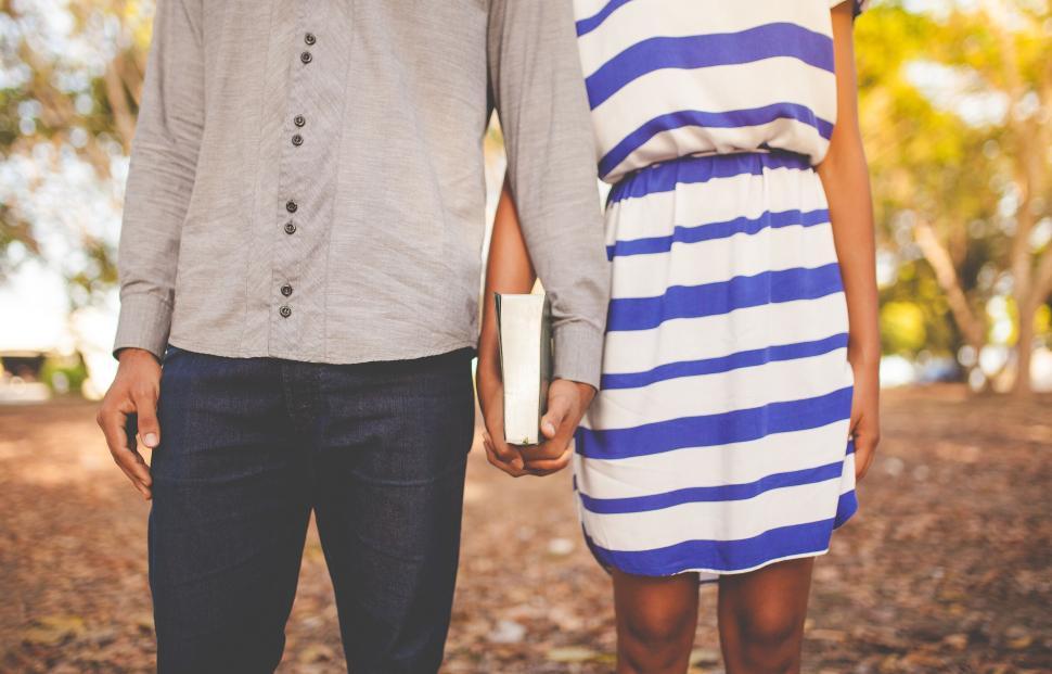 Free Image of Couple holding hands with a book in a park on an autumn day 