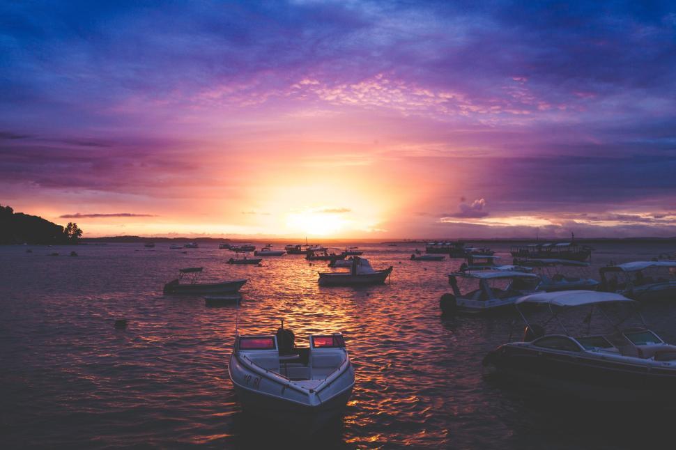 Free Image of Sunset boats floating on tranquil waters under a vivid sky 