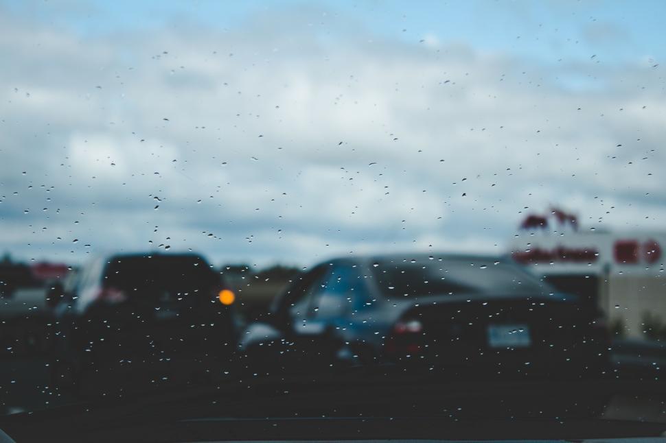 Free Image of Rain droplets on car window with blurred traffic in background 