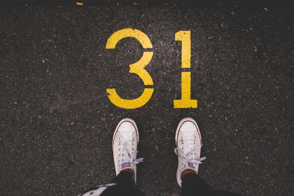Free Image of White sneakers on asphalt with yellow number 31 marking 