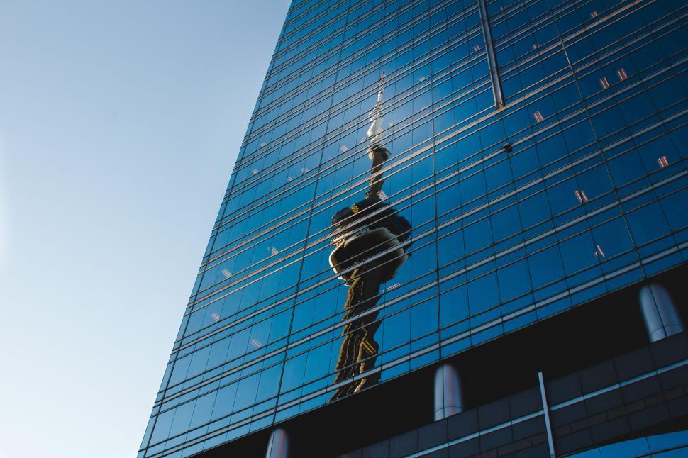 Free Image of Reflection of iconic tower on glass building against clear blue sky 