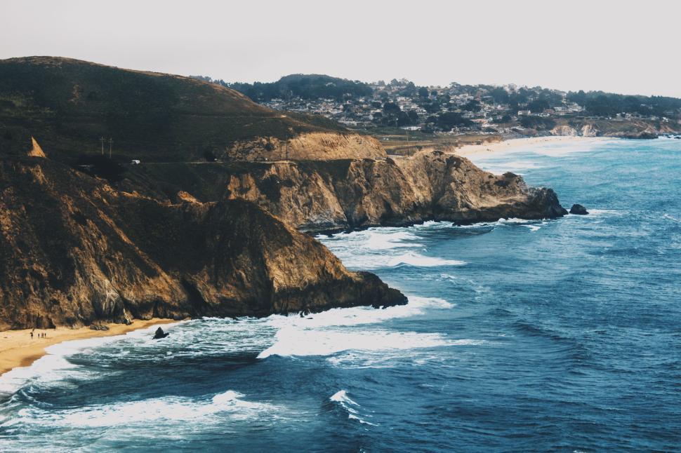 Free Image of Coastline with rugged cliffs, waves crashing against the shore 