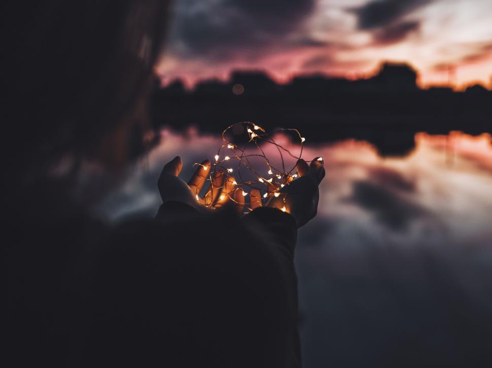 Free Image of Hands Holding Fairy Lights Against a Stunning Night Sky 