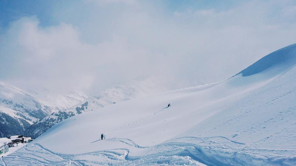 Free Image of Snow-covered mountain landscape with skiers enjoying winter sport. 