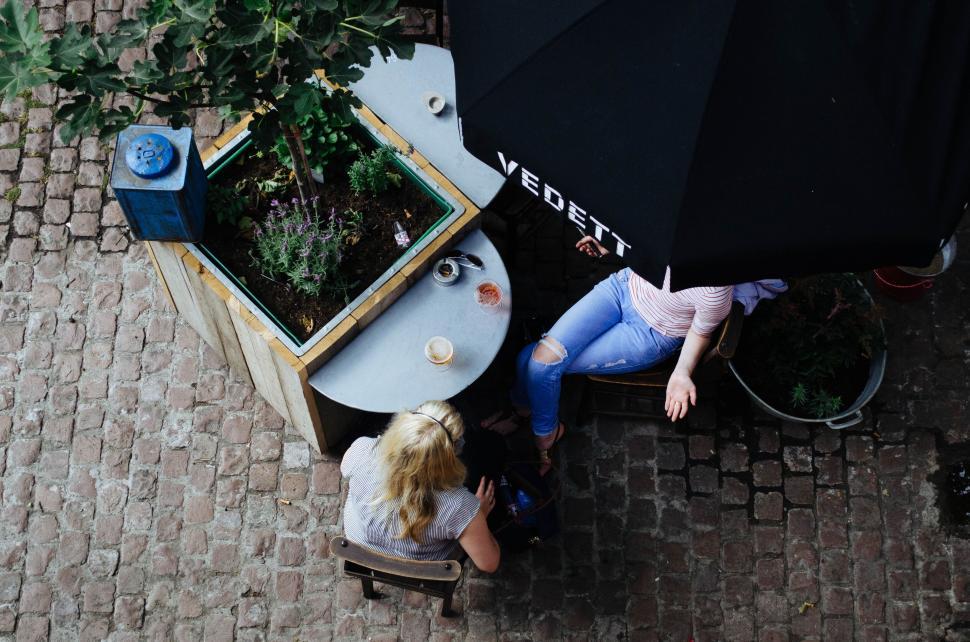 Free Image of People enjoying outdoor seating in a quaint cobblestone courtyard. 