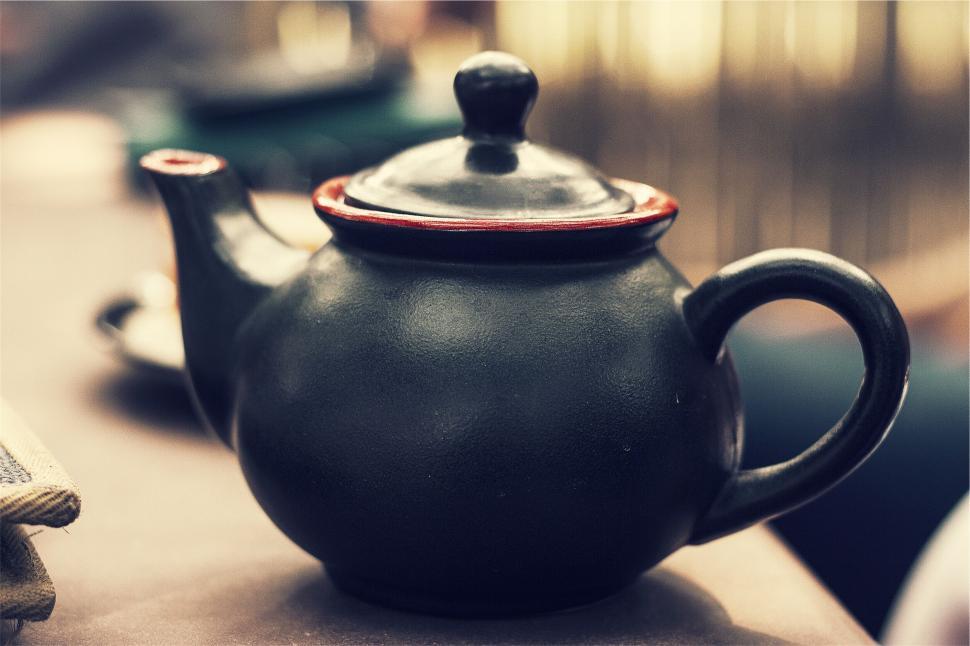 Free Image of Elegant black teapot with a hint of red on the handle, sitting on a table. 