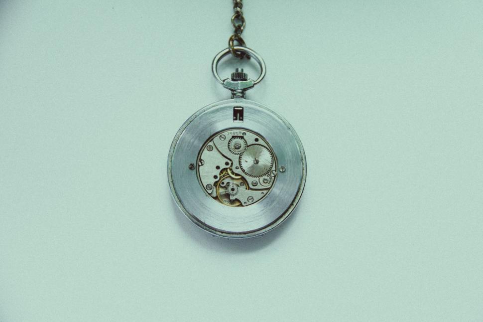 Free Image of Antique silver pocket watch with visible intricate gears and chain. 