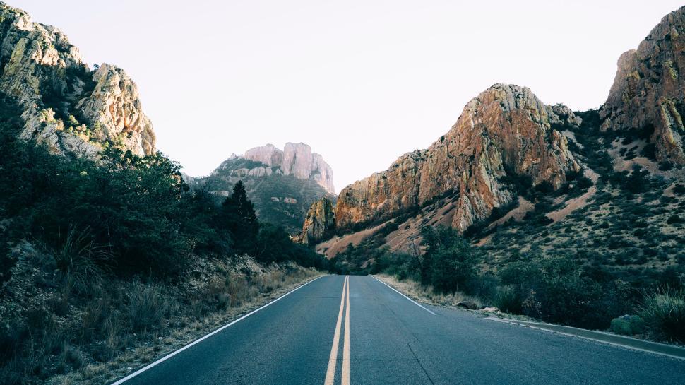 Free Image of Long open road leading through mountainous landscape at dawn. 