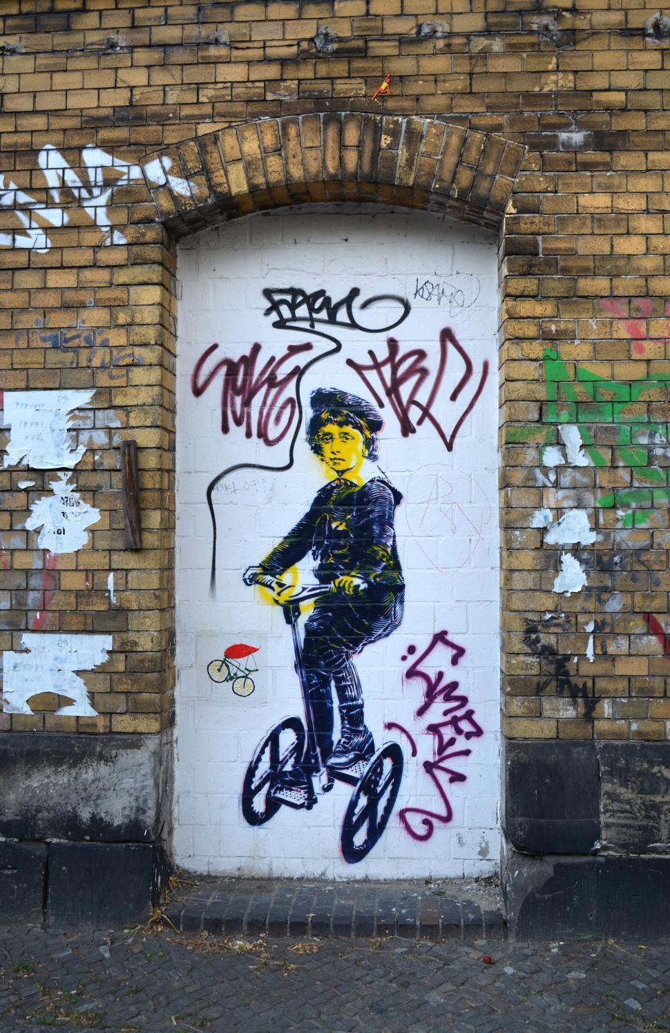 Free Image of Colorful graffiti of a boy on a bicycle on a brick wall 