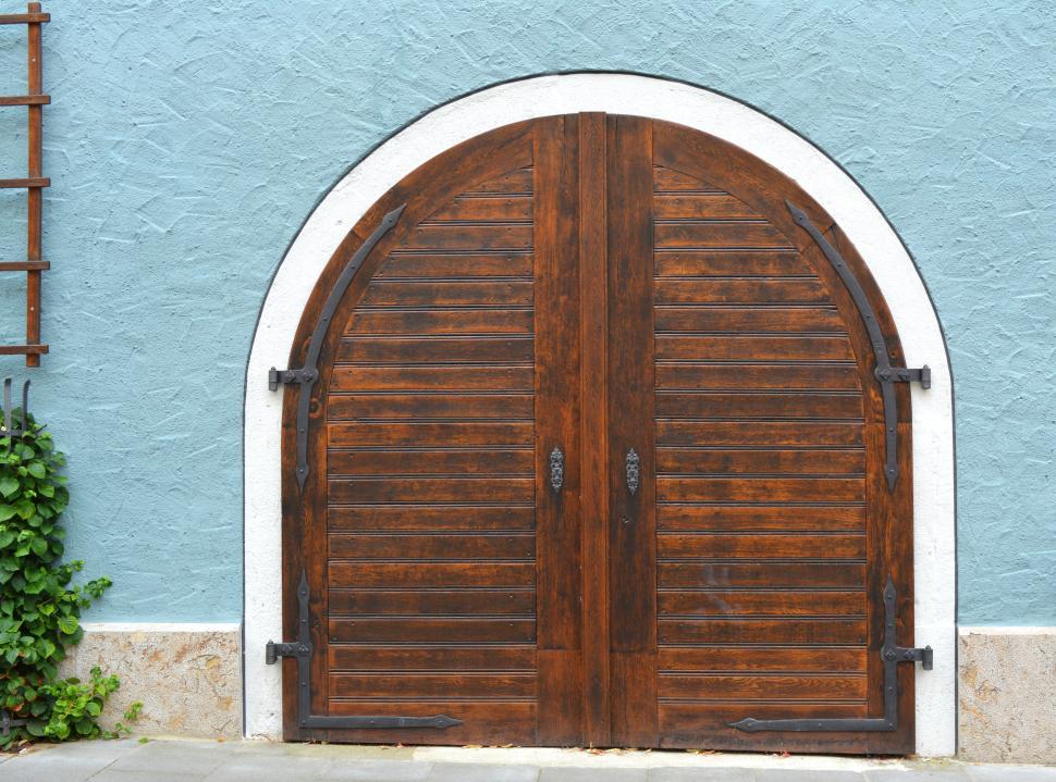 Free Image of Rustic arched wooden doors set in a light blue wall exterior 
