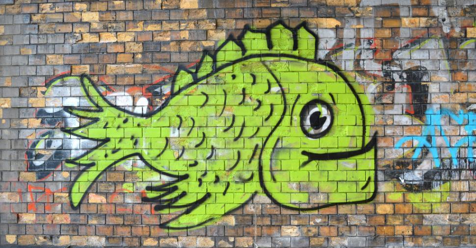 Free Image of Graffiti of a cheerful green fish on a brick wall background 
