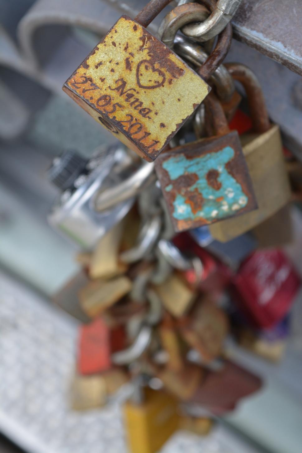 Free Image of Close-up of rusty love locks inscribed with names and dates on a chain. 