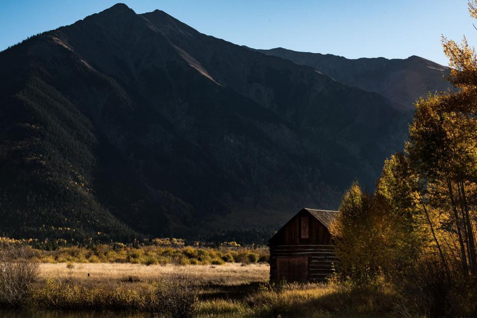 Free Image of Rustic cabin in fall landscape with mountain backdrop 