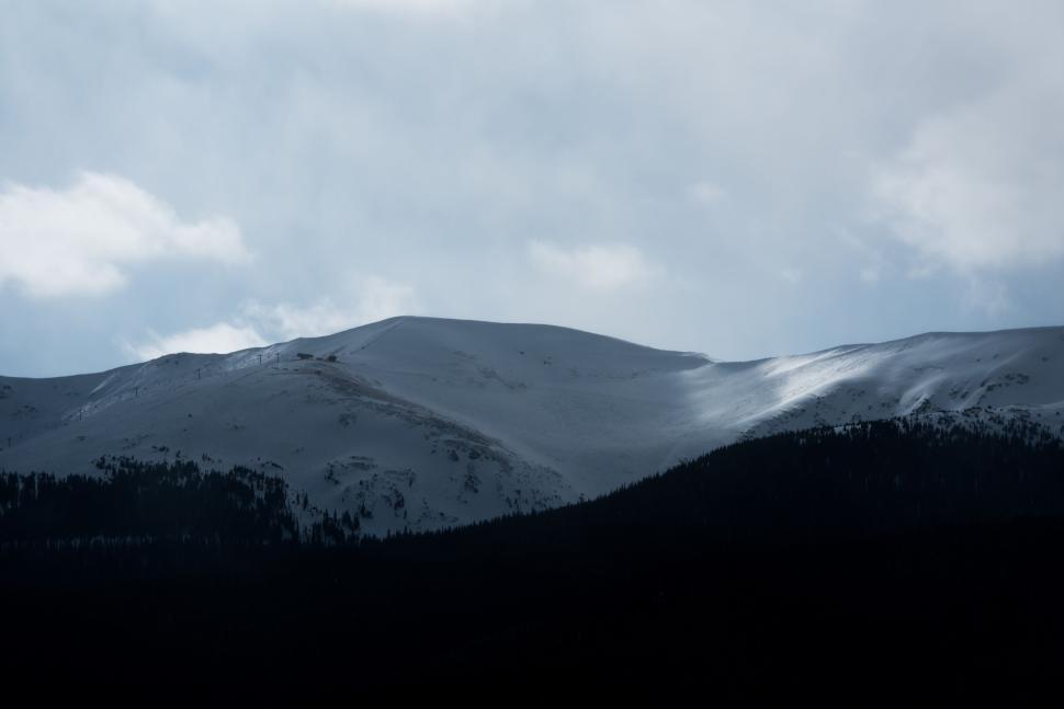 Free Image of Snow-covered mountains under a partially cloudy sky. 