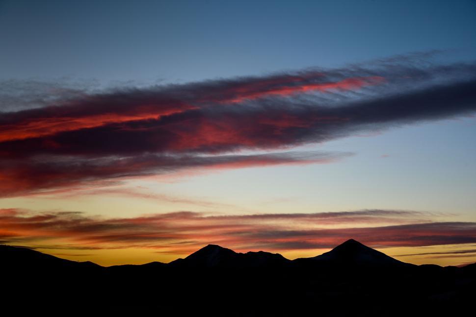 Free Image of Vivid sunset paints the sky over silhouette mountains 