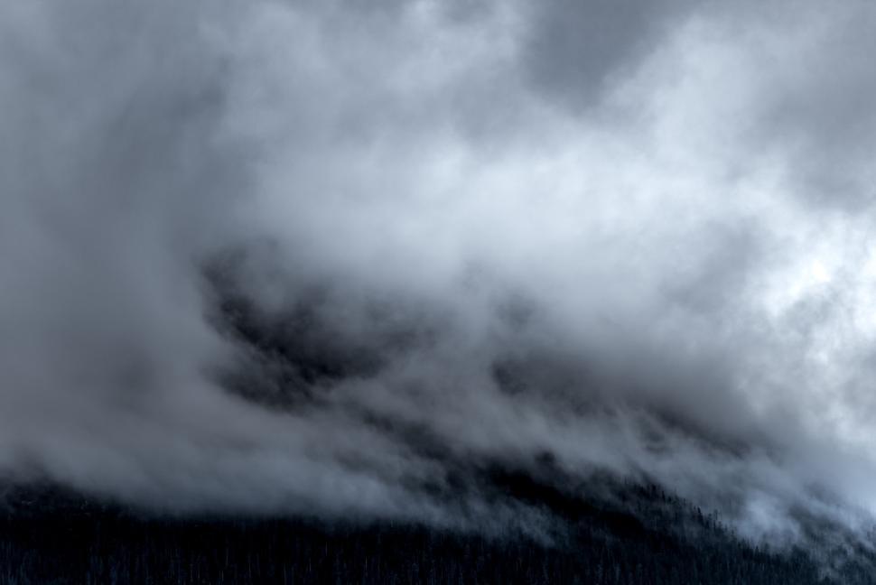 Free Image of Foggy mountain slope partially obscured by clouds. 